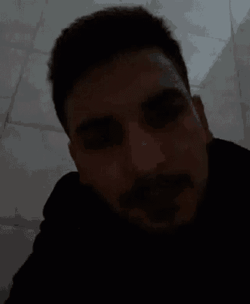 a man with a beard is looking at the camera in the dark