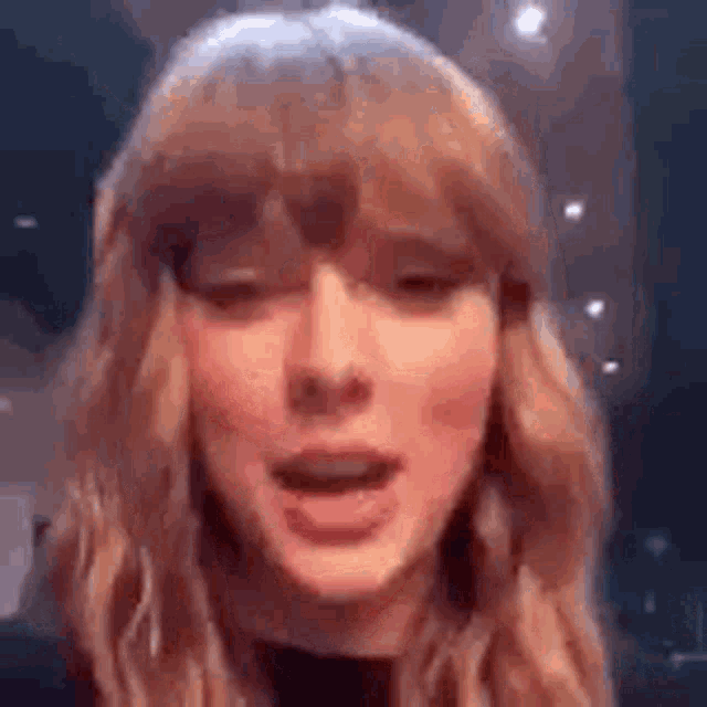 a close up of a woman 's face with her mouth open and a blurred background .