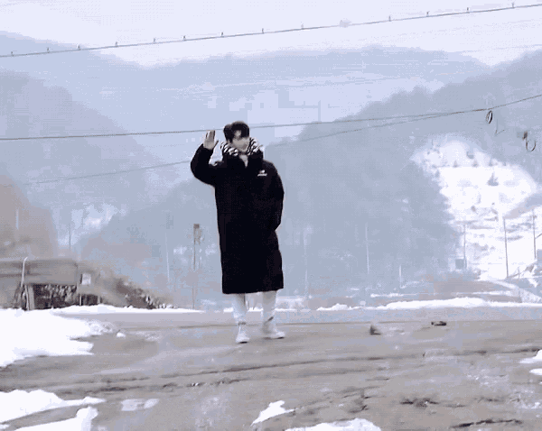a man in a black coat is waving his hand
