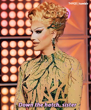 a drag queen says down the hatch sister in front of a crowd of lights