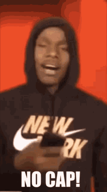 a man wearing a hoodie that says new york is holding a cell phone