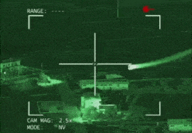 a helicopter is flying through the air at night with a sniper scope on it .