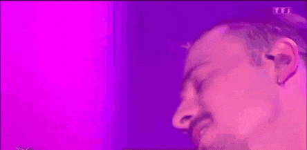 a man with a beard is making a funny face in front of a purple light .