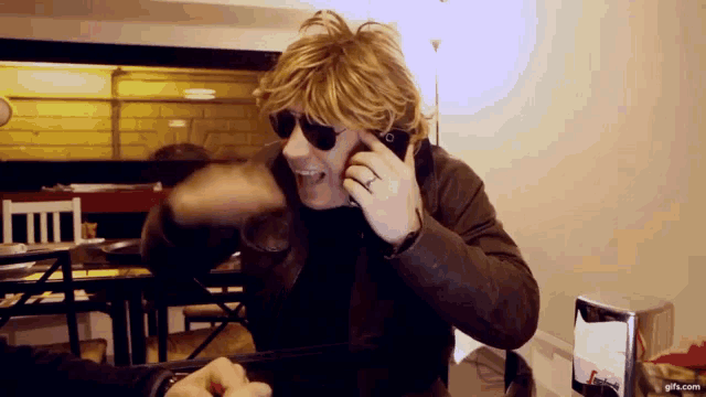 a man wearing sunglasses is talking on a cellphone