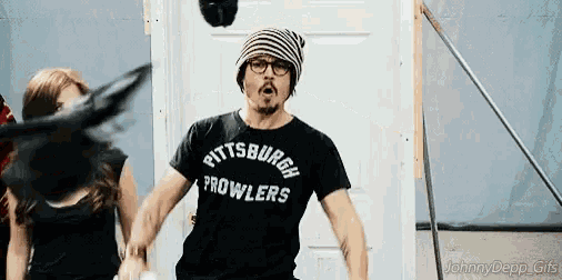 a man wearing a pittsburgh prowlers t-shirt stands in front of a door