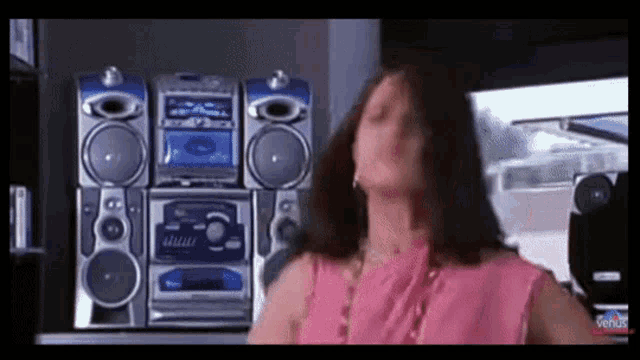 a woman in a pink top is dancing in front of a panasonic stereo system