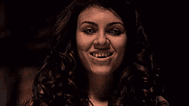 a woman with long curly hair is making a funny face .