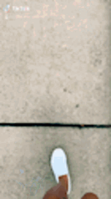 a person is walking on a sidewalk wearing white sneakers .