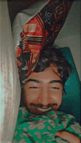 a man with a beard is smiling while laying under a curtain