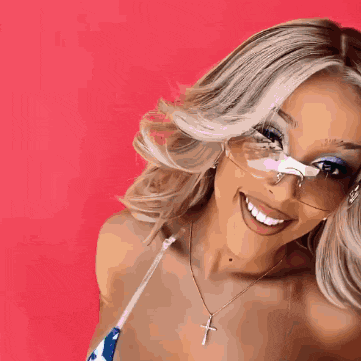 a woman wearing glasses and a cross necklace smiles for the camera