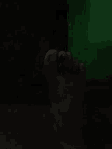 a person 's hand is visible in the dark in front of a green background .