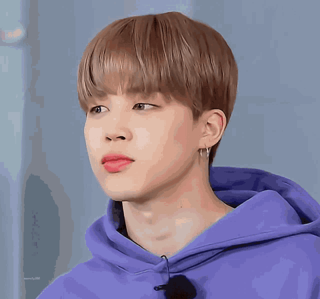 a close up of a person wearing a purple hoodie and hoop earrings