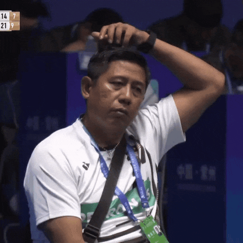 a man adjusts his hair while wearing a lanyard that says ' sydney ' on it