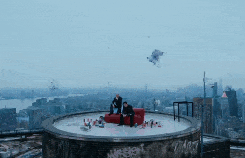 a man sits on a red couch on top of a circular building with graffiti on it that says " mission "