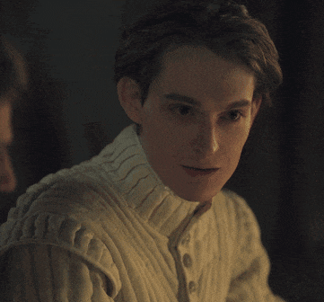 a man wearing a white sweater with buttons on the sleeves