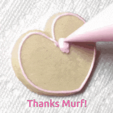 a heart shaped cookie being decorated with pink frosting and the words thanks murf