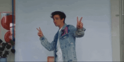 a man in a denim jacket is making a peace sign with his hands .