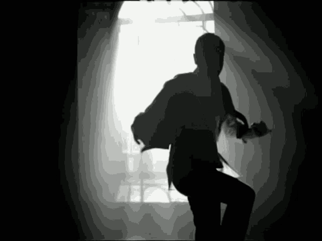 a silhouette of a man in a suit dancing in front of a window