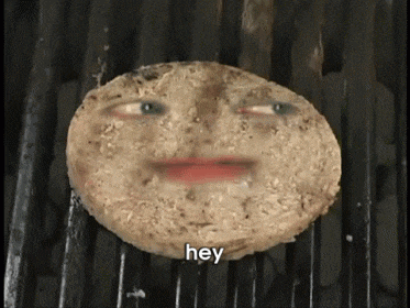 a hamburger patty with a face on it is cooking on a grill and says hey