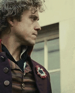 a man with curly hair is wearing a purple jacket with buttons