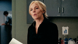 a woman in a black shirt is holding a piece of paper in her hand