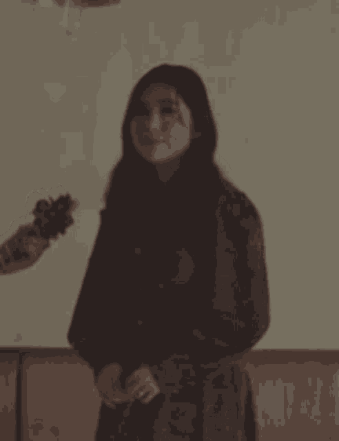 a woman in a dress is standing in front of a couch holding a microphone .