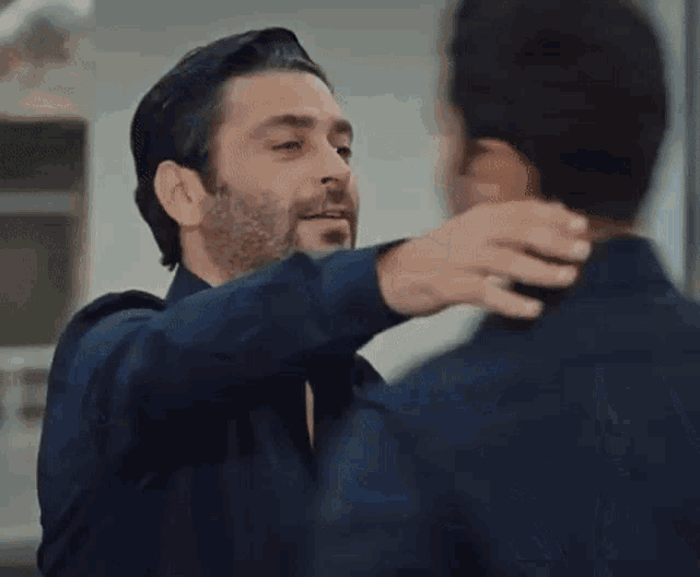 two men are hugging each other in front of a group of men in suits .