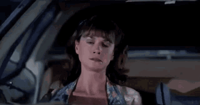 a woman is sitting in a car with the words `` that son of a bitch '' written on the screen .