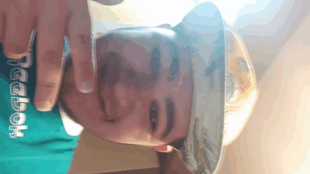 a person wearing a reebok shirt holds their hat over their face