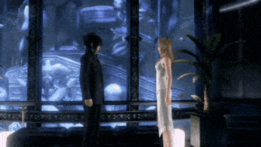a man in a suit and a woman in a white dress are standing in front of a window