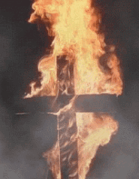 a cross is on fire in the dark with smoke coming out of it