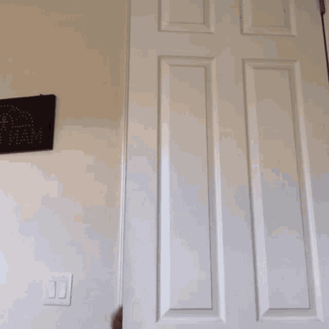 a man is peeking out of a white door