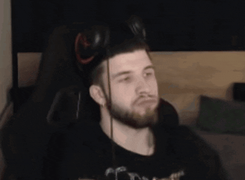 a man with a beard is wearing headphones while sitting in a chair .