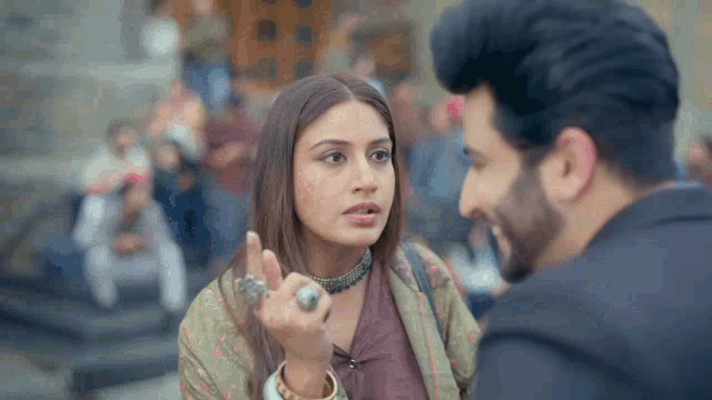 a man and a woman are talking to each other and the woman is wearing a choker .
