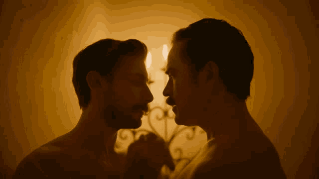 two men without shirts are looking at each other