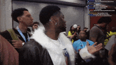 a man in a white fur coat stands in a crowd of people with a hashtag that starts with the letter r