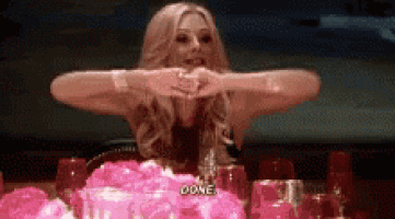 a woman is sitting at a table with a cake and glasses and says `` done '' .