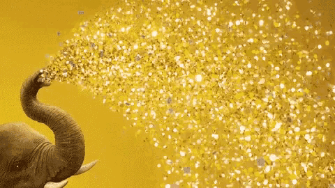 an elephant is blowing gold confetti out of its trunk .
