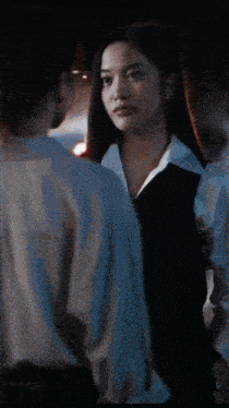 a woman is holding a baby in her arms in a dark room while another woman looks on .
