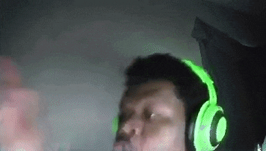 a man wearing green headphones is making a funny face in a dark room .