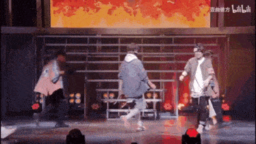 a group of people are dancing on a stage in front of a big screen .
