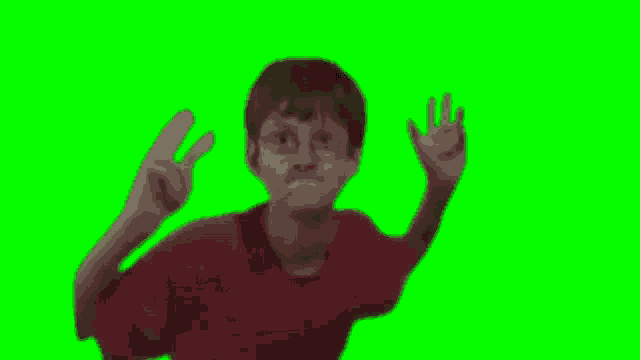 a young boy wearing glasses and a red shirt is jumping in the air on a green screen .