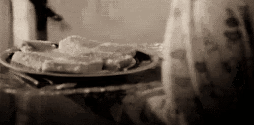 a plate of food is sitting on a table with a person walking in the background .
