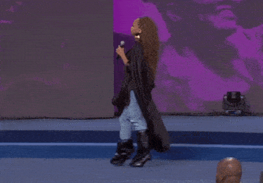a woman is kneeling down on a stage with a microphone