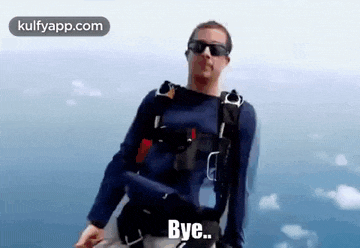a man wearing sunglasses and a parachute is standing in the air and says `` bye '' .