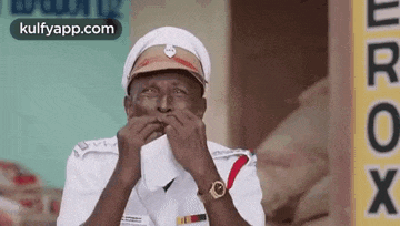 a man in a police uniform is covering his mouth with his hands while wearing a watch .