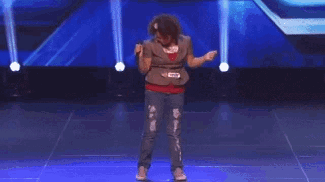a woman is standing on a stage with a microphone in her hand .