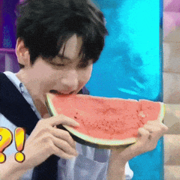 a young man is eating a large slice of watermelon .