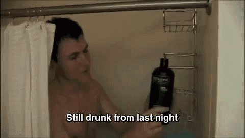 a shirtless man is taking a shower while holding a bottle of tresemme shampoo ..