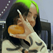 a woman with green hair is eating a doughnut